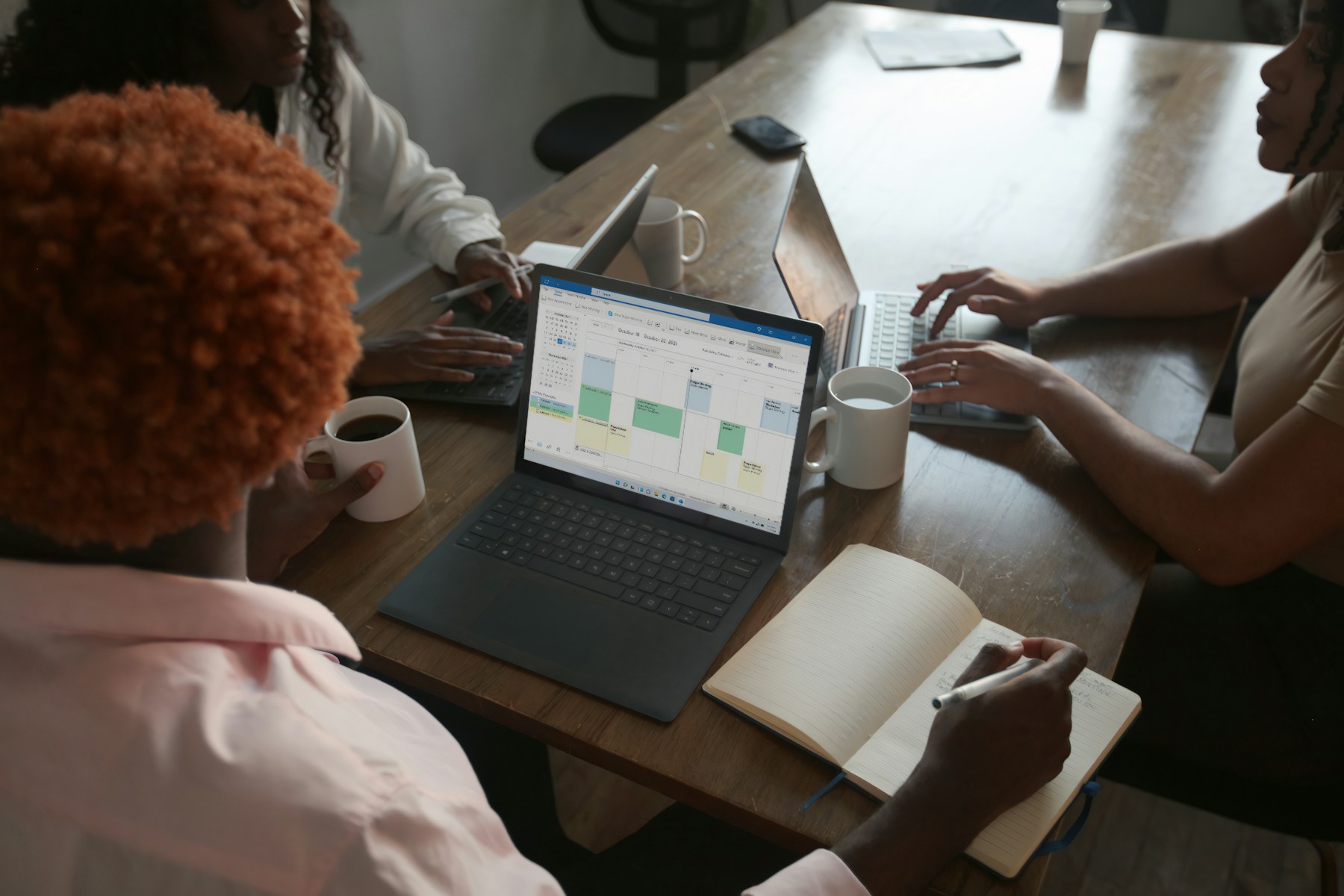 Three colleagues discussing results on a laptop in a meeting